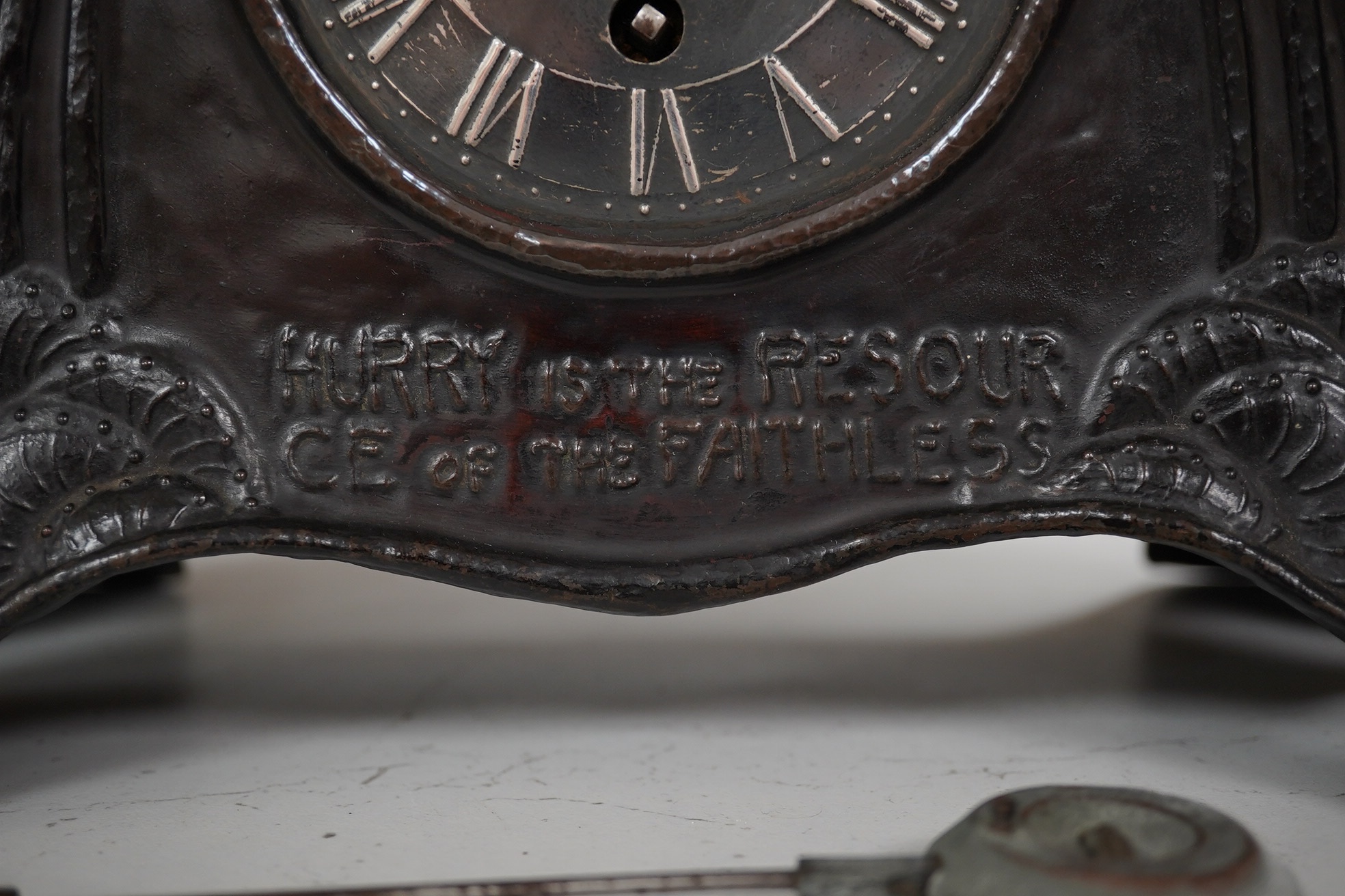 An Arts & Crafts embossed copper mantel timepiece, probably Glasgow School of Art, c.1900, with pewter dial, the text under the dial reads; ‘Hurry is the resource of the faithless’, 21.5cm high. Condition - fair, restora